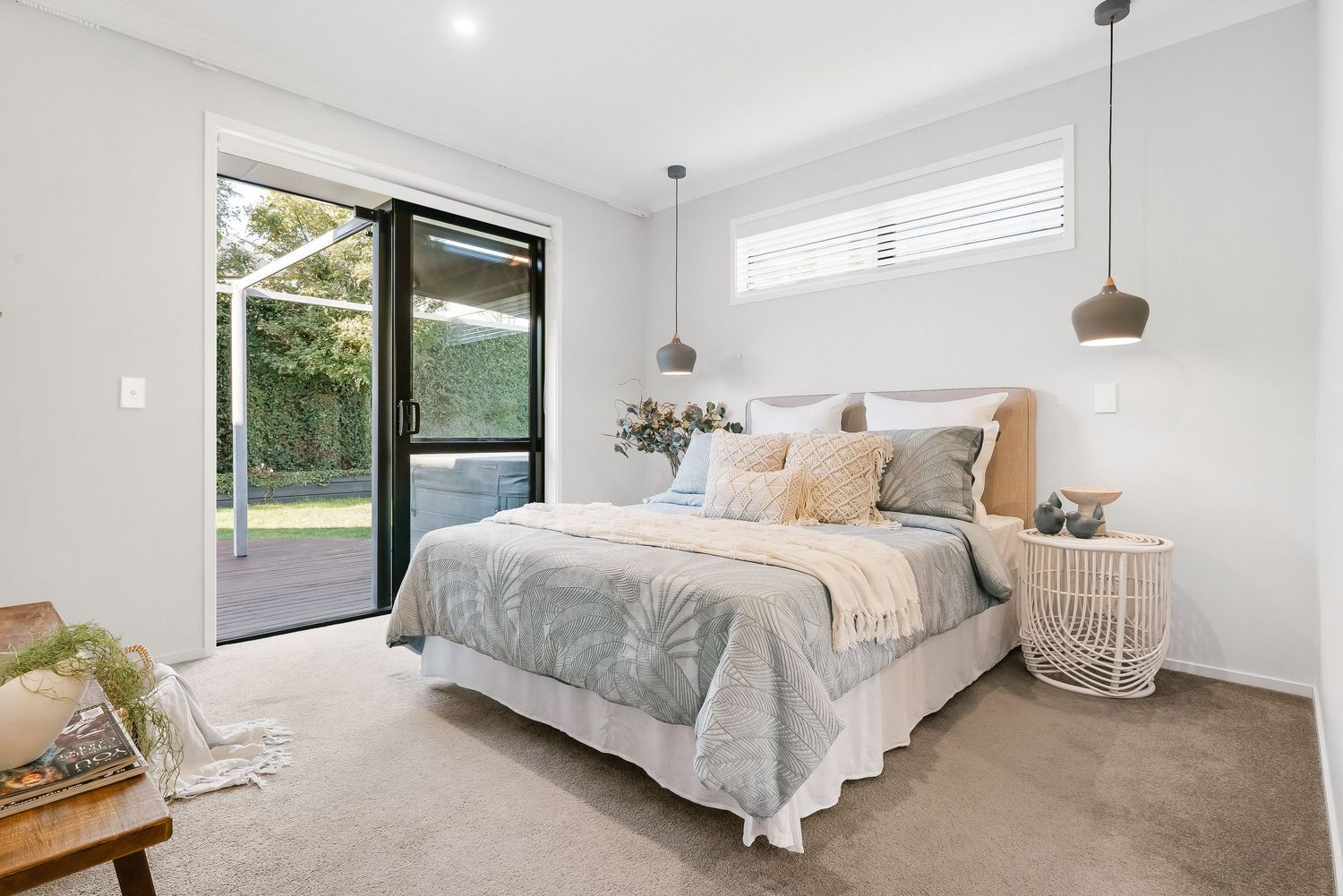 Modern bedroom with white walls, pendant lights, and panoramic windows offering natural light and scenic views.