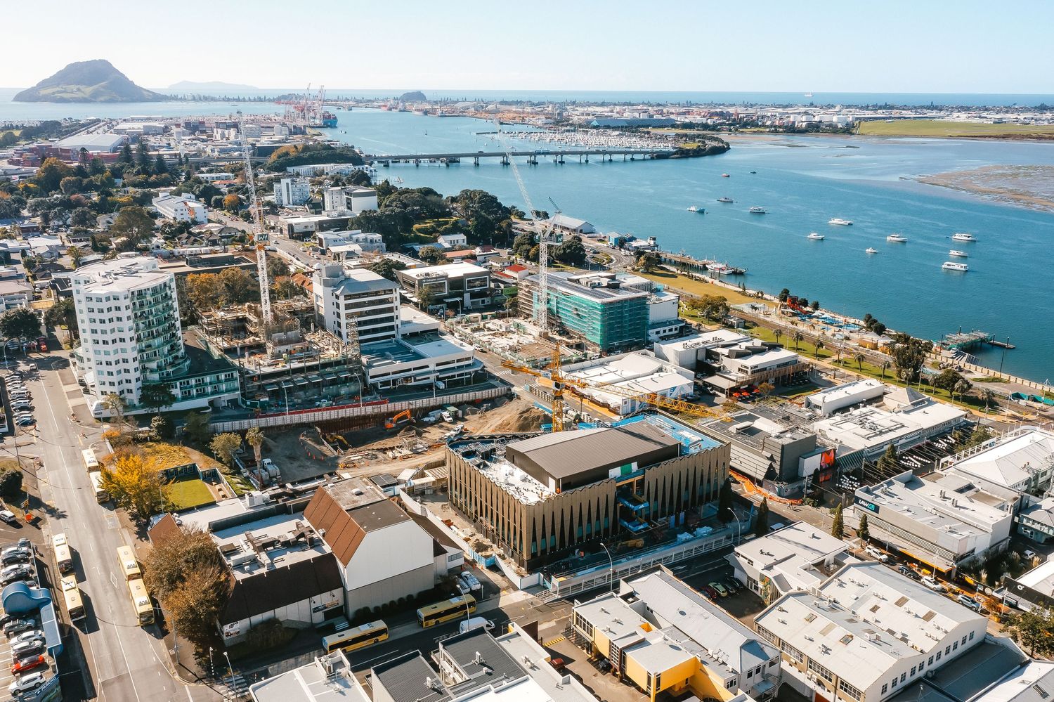 Panoramic coastal cityscape showing harbor, boats, and urban development along the waterfront.