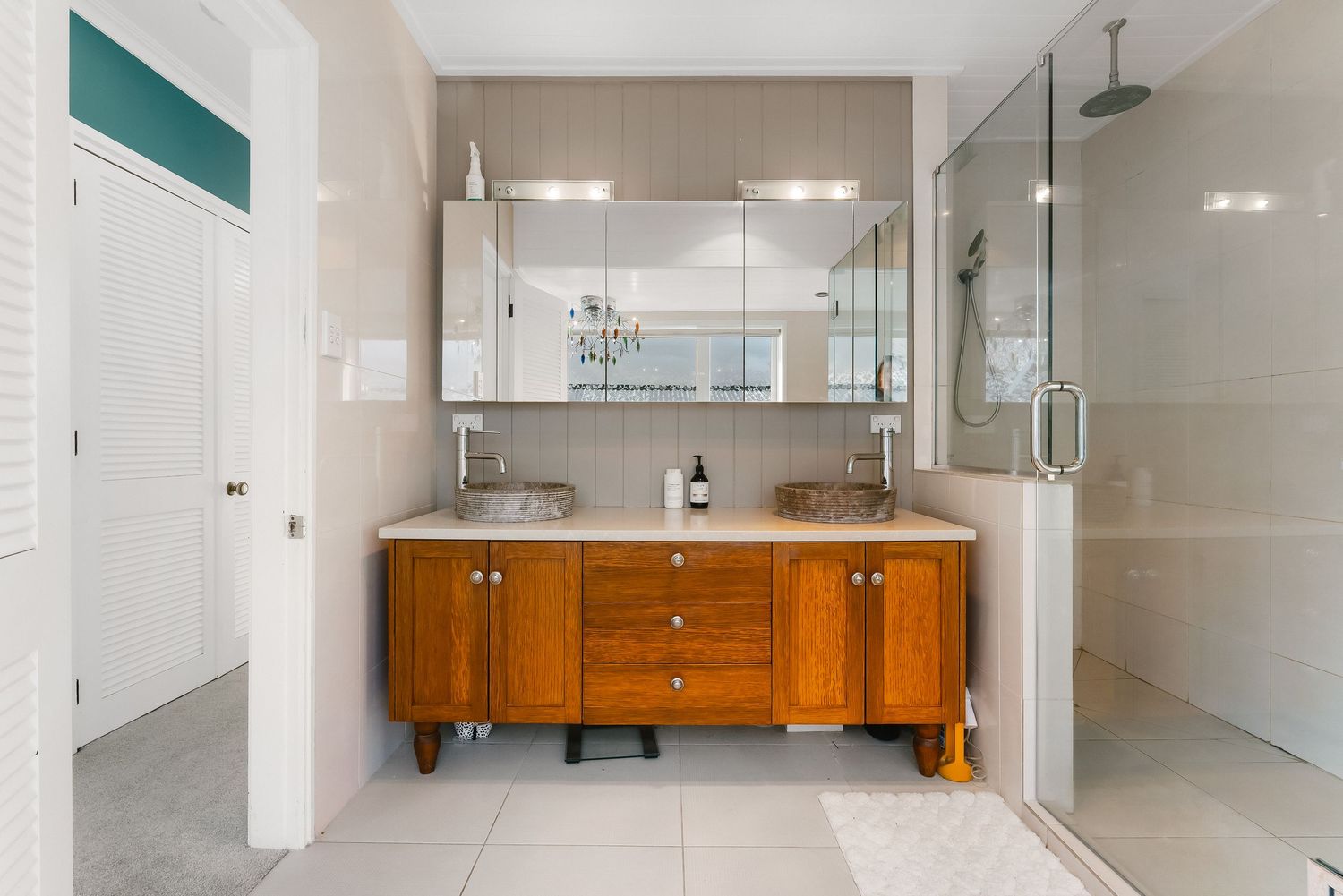 Modern white bathroom interior with wooden vanity and minimalist design elements.