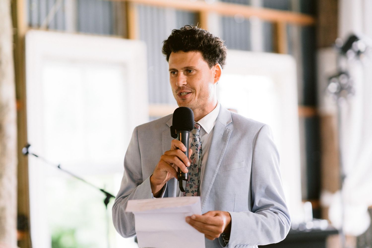 Wedding reception speeches being given inside a bright, elegant venue.