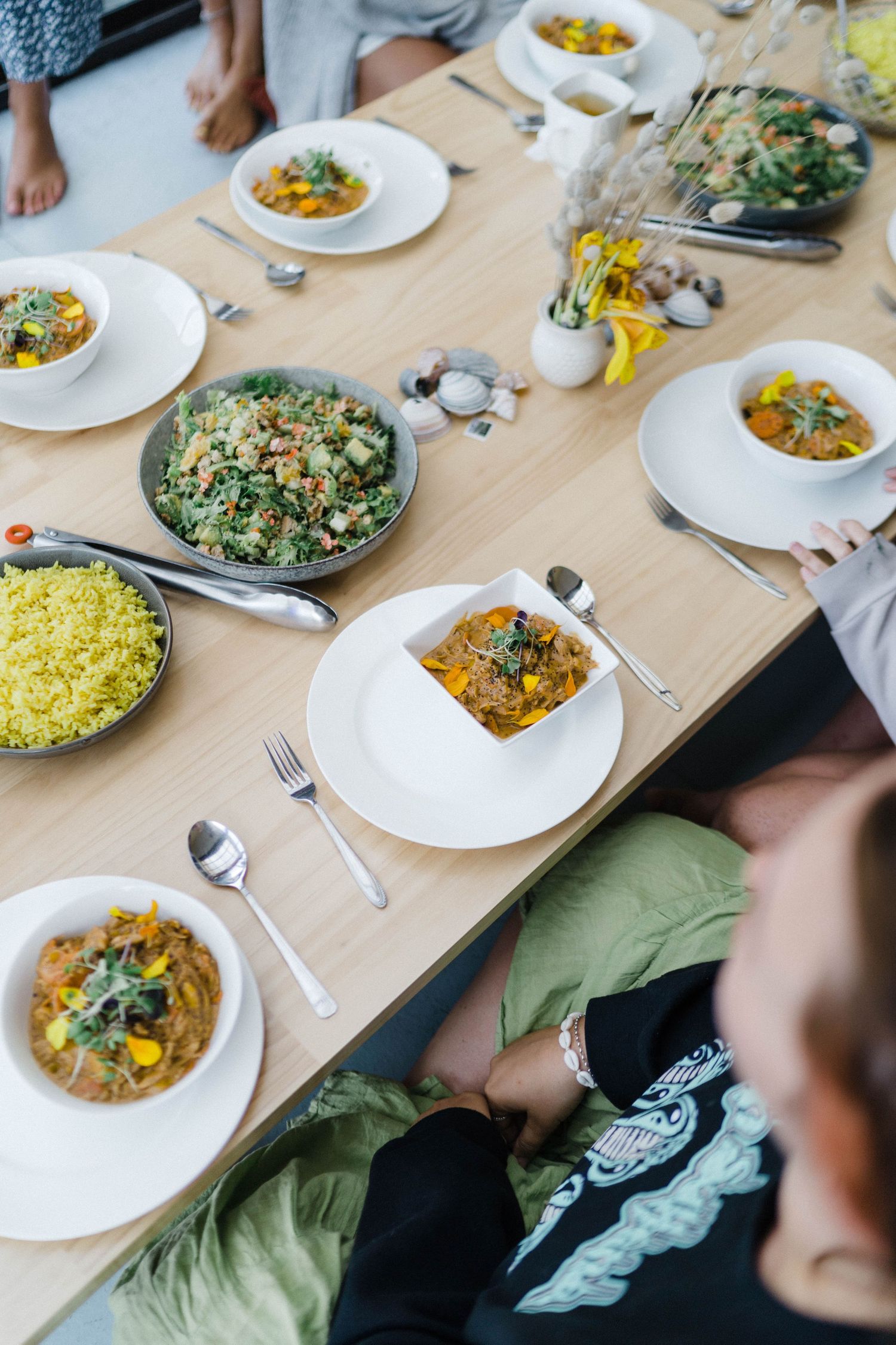 Overhead view of a dining table set with colorful curry dishes and rice bowls.