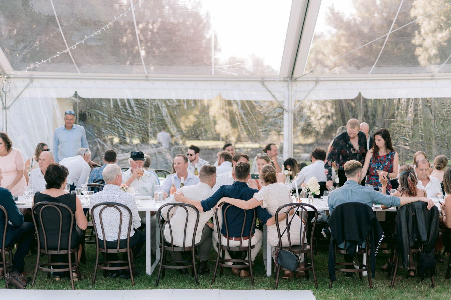 Wedding reception dining area under a tent with tables set for guests.