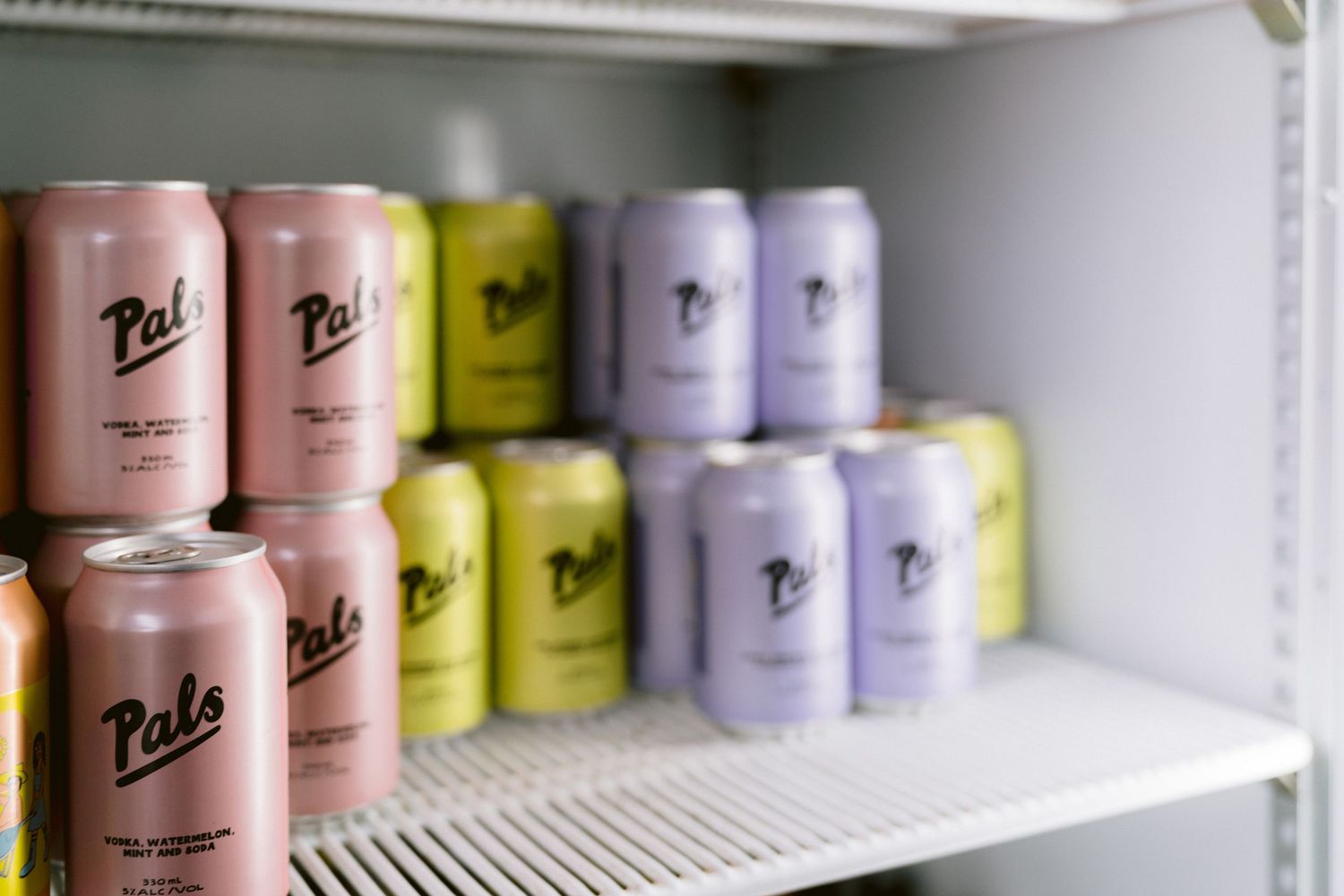 Rows of colorful beverage cans arranged neatly on white shelves.