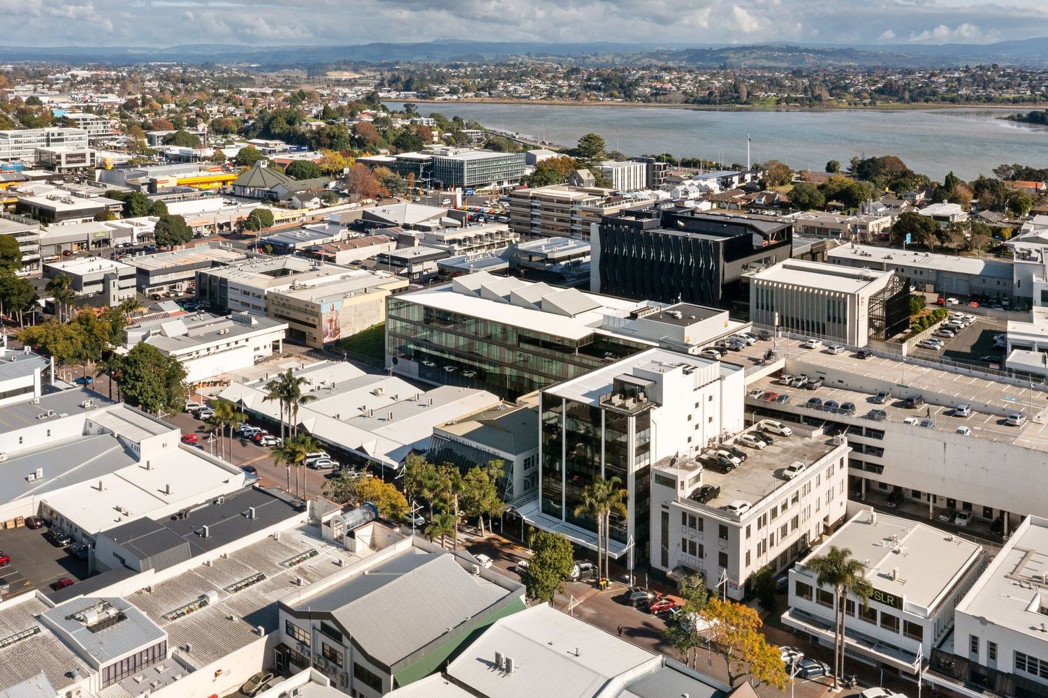 Aerial view of commercial buildings and waterfront development in coastal urban area with white rooftops.