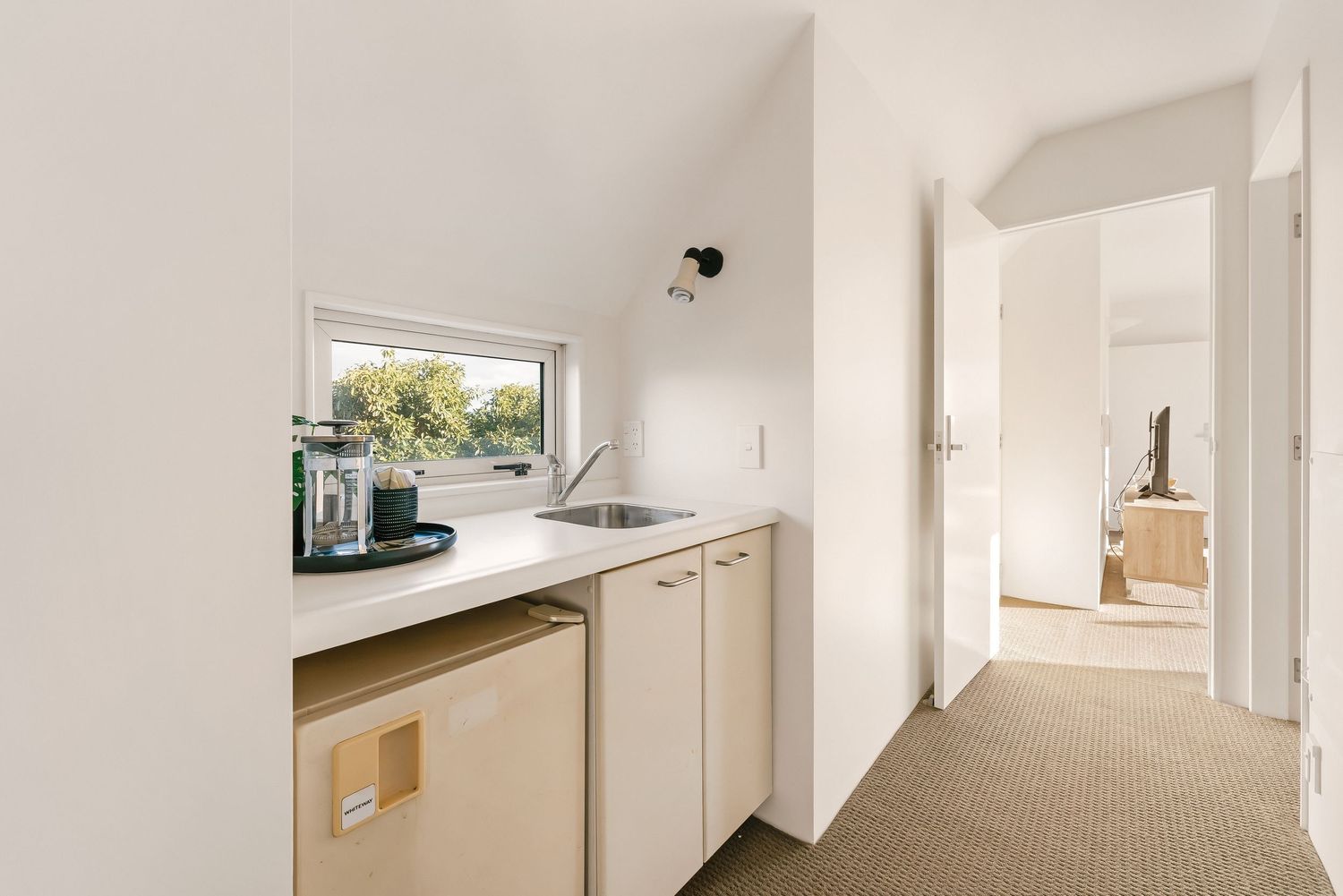 White hallway with kitchenette featuring mini fridge and counter space.
