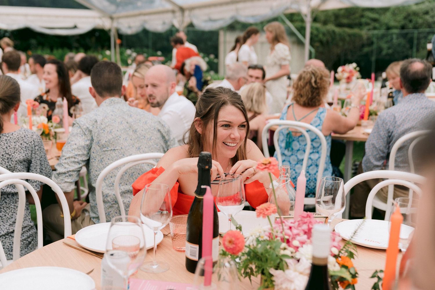 Wedding reception dining setup with guests at tables under open sky.