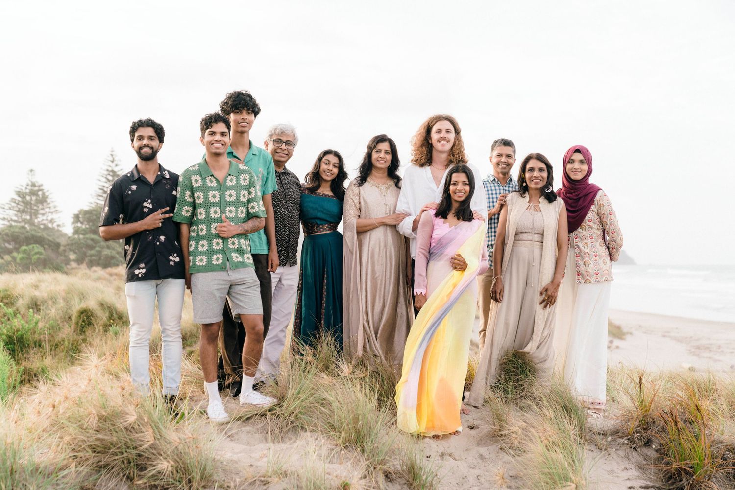 Group photo of friends on a beach cliff wearing coordinated neutral and pastel outfits.
