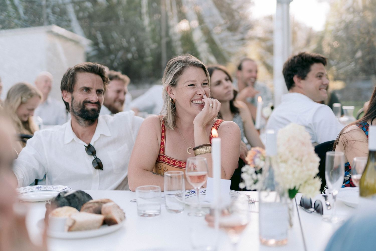 Wedding guests laughing and enjoying themselves at an outdoor reception dinner.