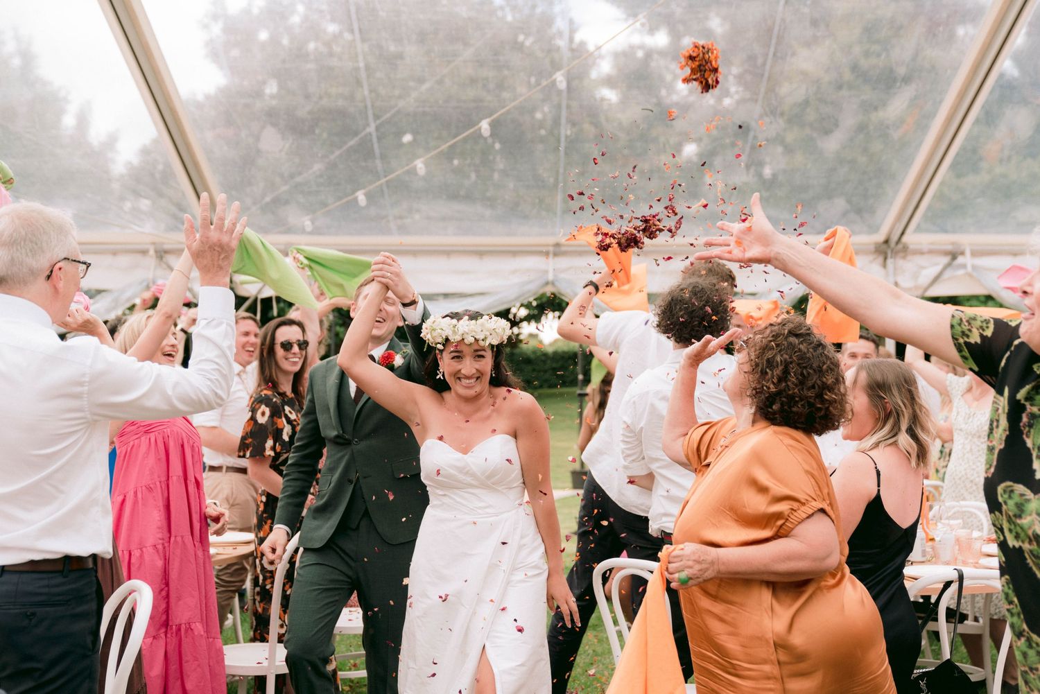Celebratory moment at a wedding reception with confetti flying under a white tent.
