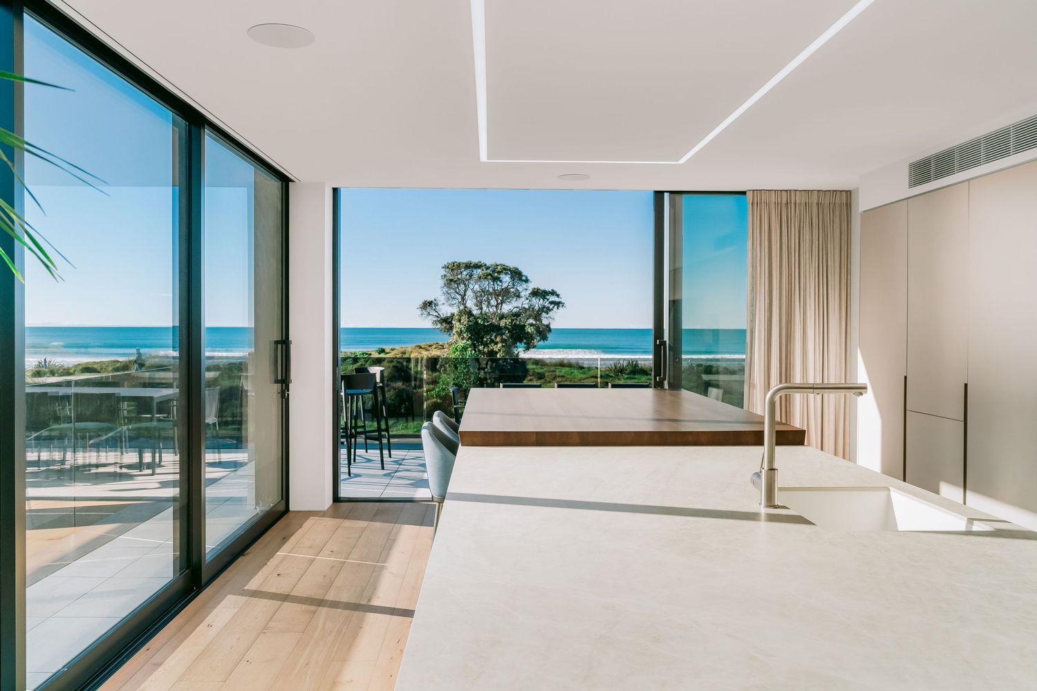 Sleek coastal apartment interior with full-length windows offering expansive beach and ocean views.