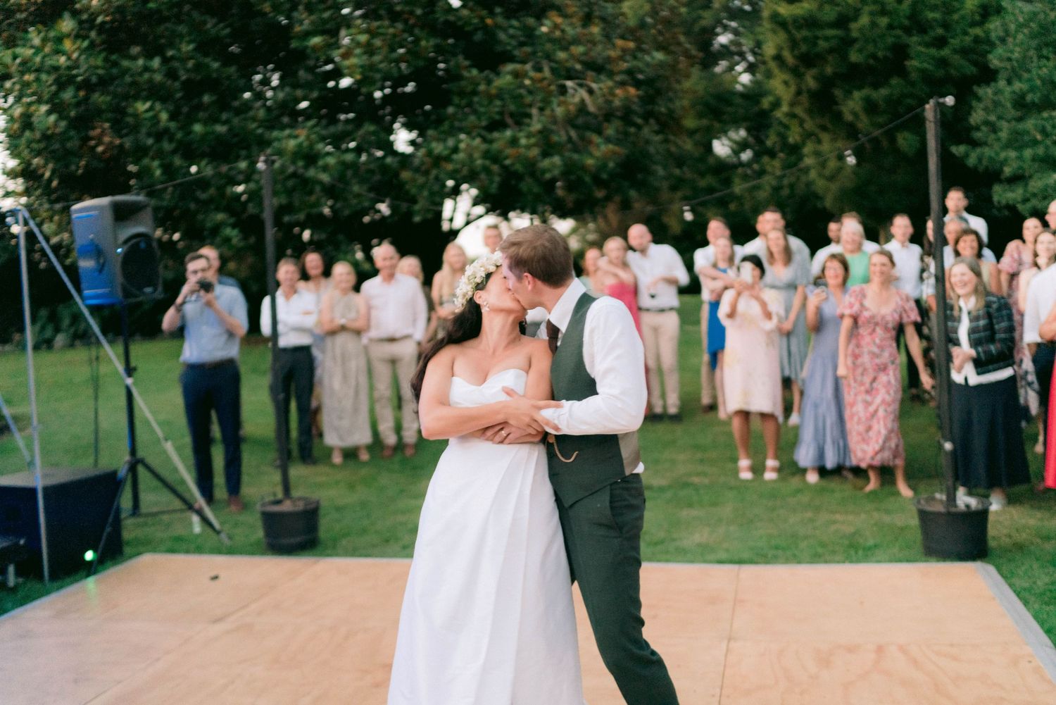 Couple sharing their first dance on an outdoor dance floor at twilight.