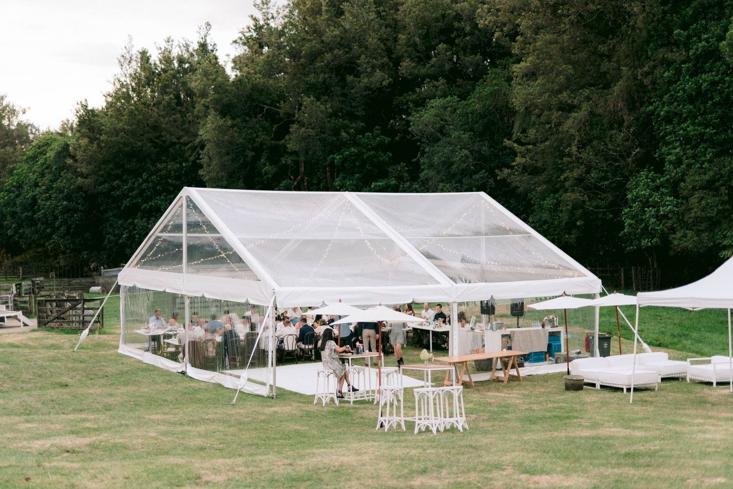 Aerial view of white wedding tents and reception setup in a scenic countryside location.