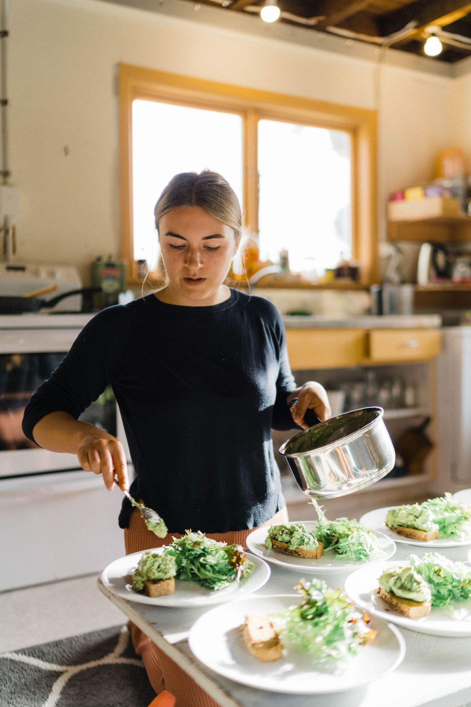 Plating elegantly prepared salads in a bright modern kitchen.