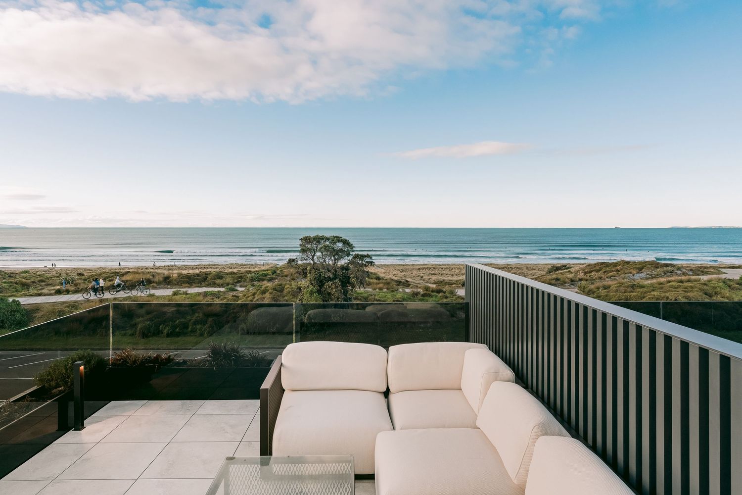 Panoramic oceanfront terrace with white outdoor furniture and coastal views stretching to the horizon.
