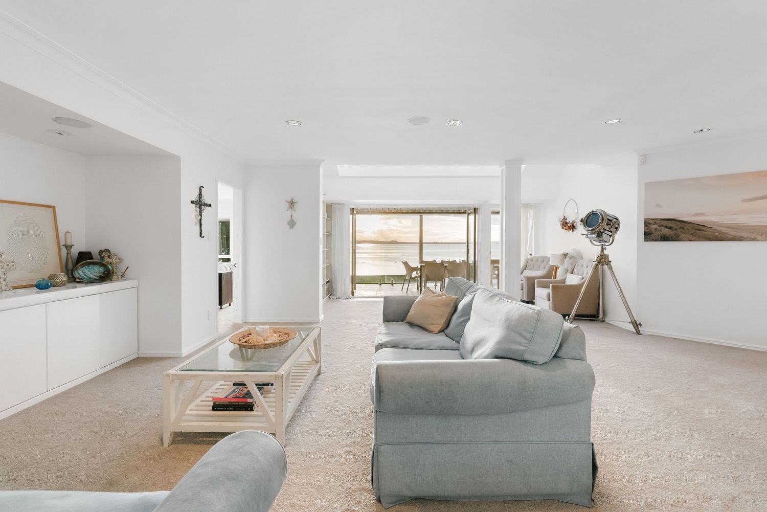 Bright coastal living room with comfortable seating and modern decor facing large windows.