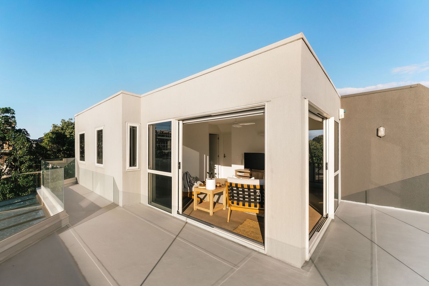 Modern white building exterior with clean lines and large windows featuring outdoor living spaces.