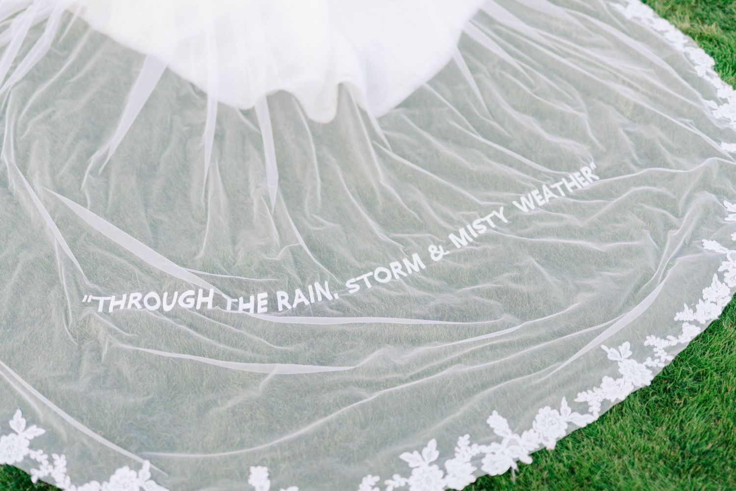 Close-up details of an ornate white wedding dress veil with delicate lace patterns.