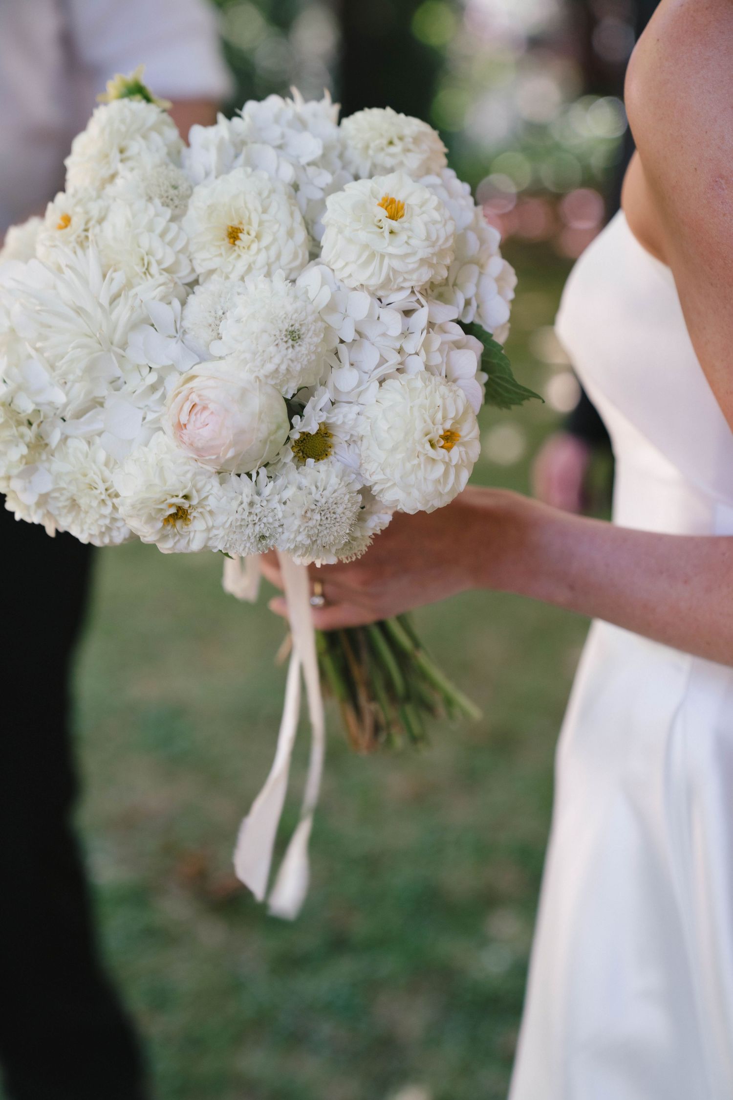 Close-up of an elegant white peony and garden rose bridal bouquet with ribbon.