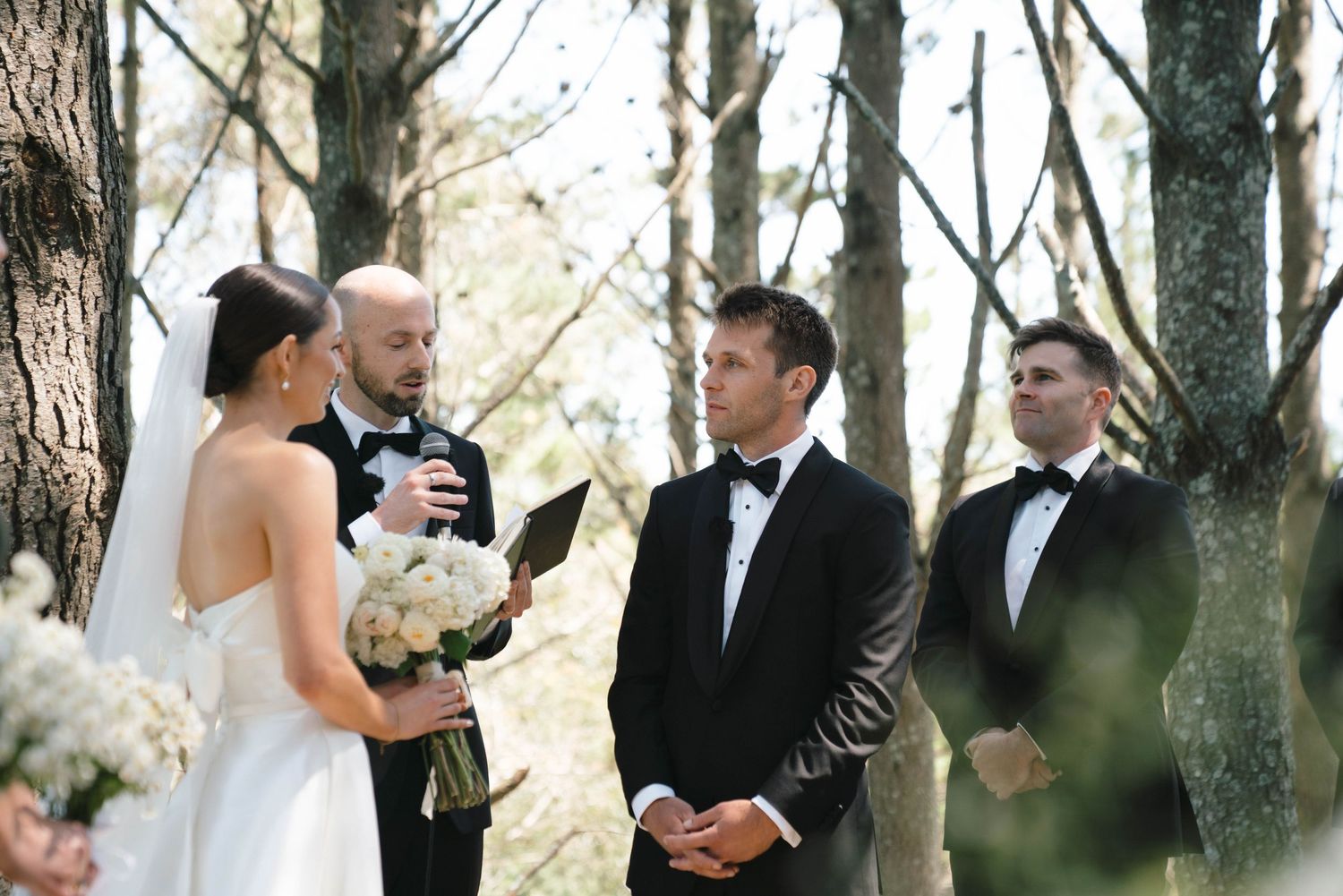 An intimate forest wedding ceremony surrounded by towering pine trees.