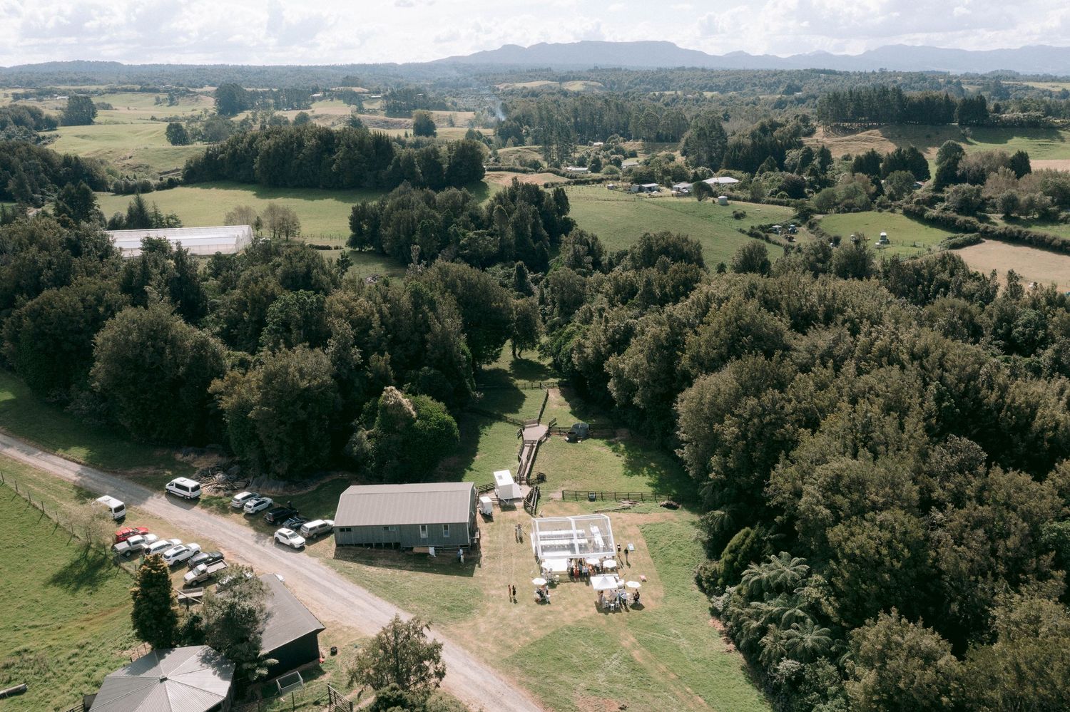 Aerial panoramic view of rolling countryside with scattered buildings and forests.