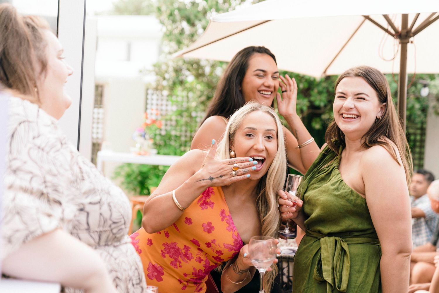 Friends sharing laughter and smiles at an outdoor garden party.