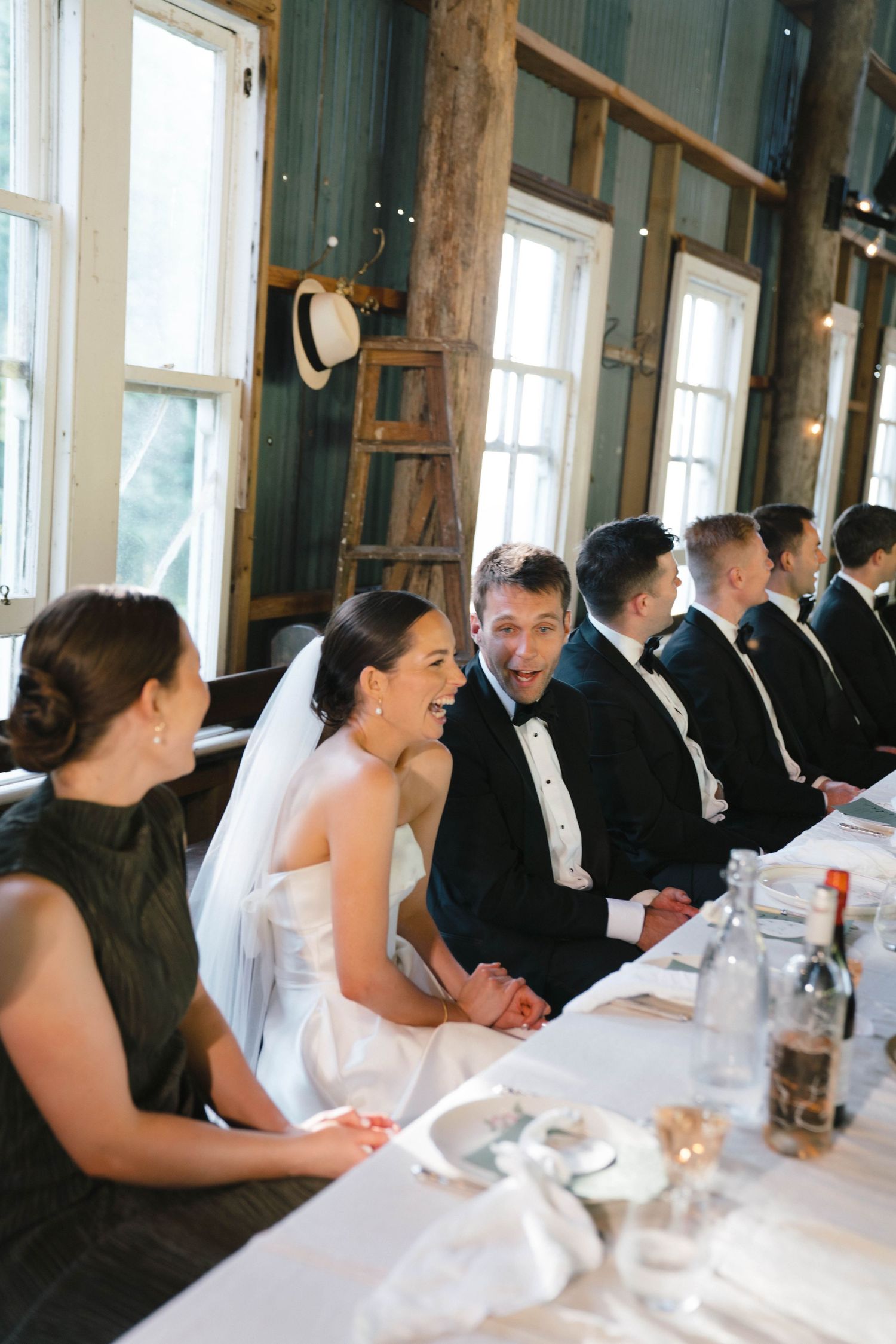Wedding reception guests seated at long tables in an elegant indoor venue.