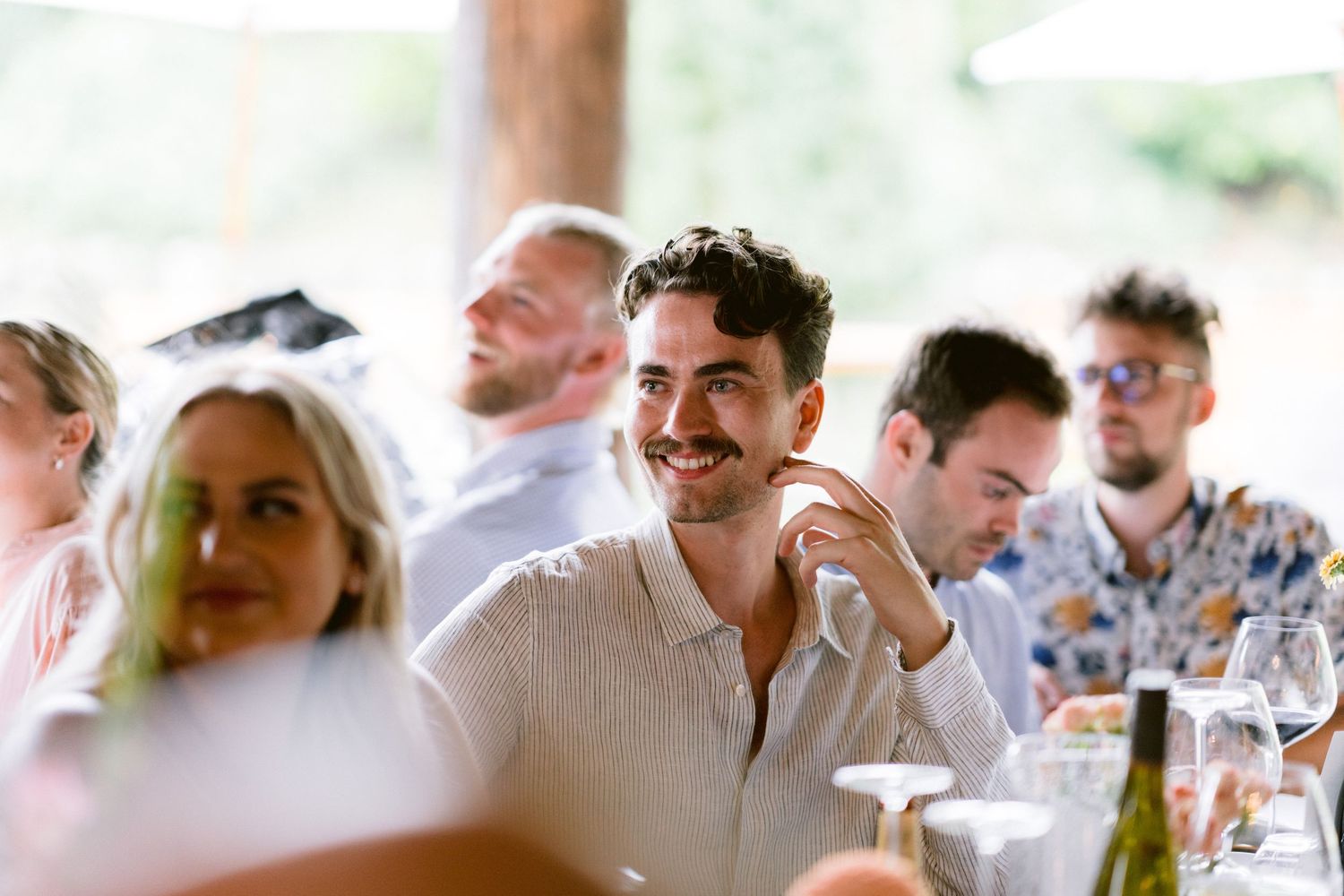 Wedding reception guests enjoying conversation at decorated dining tables.