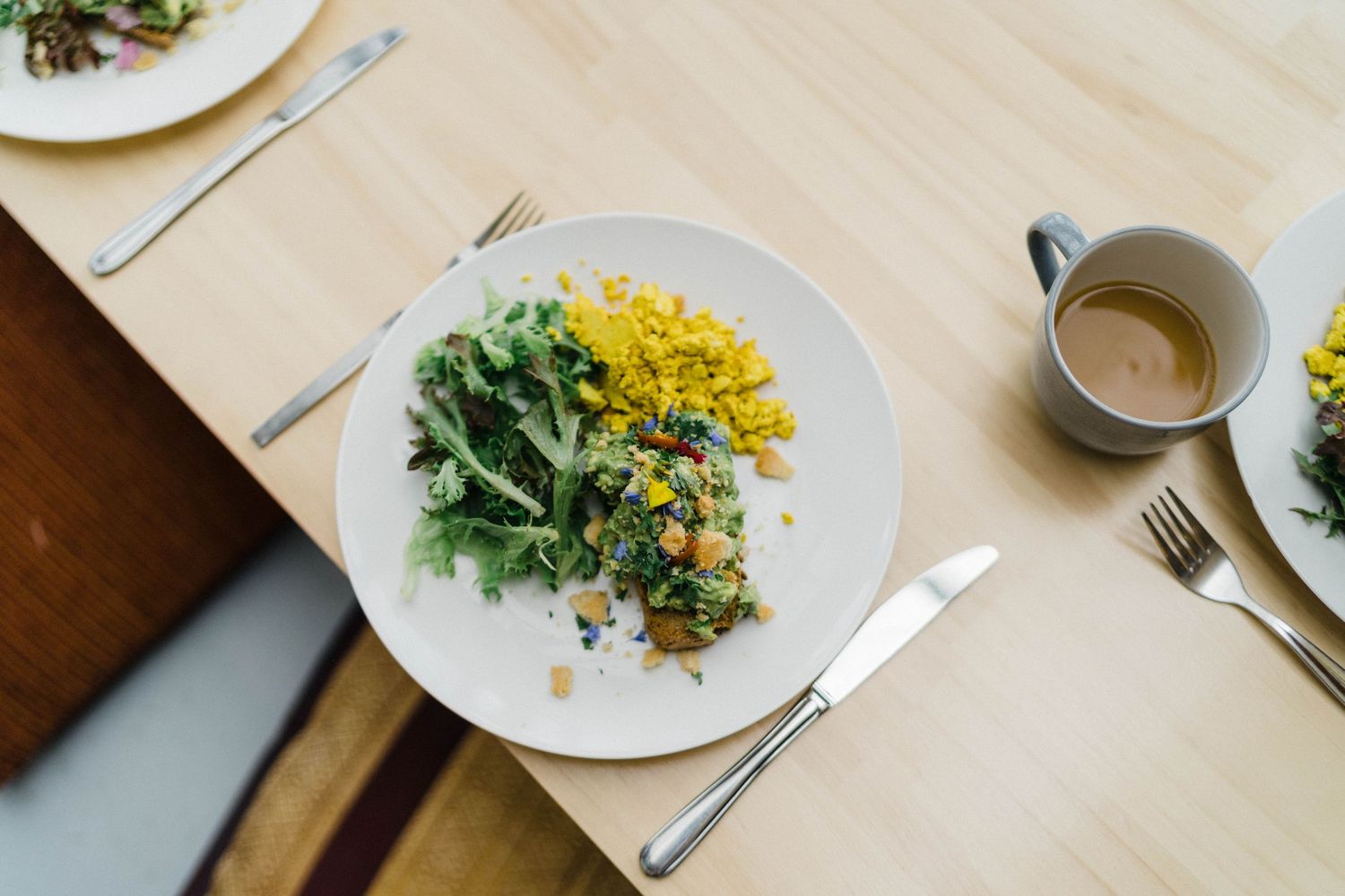 Fresh salad with yellow corn and green herbs plated elegantly on white dish.