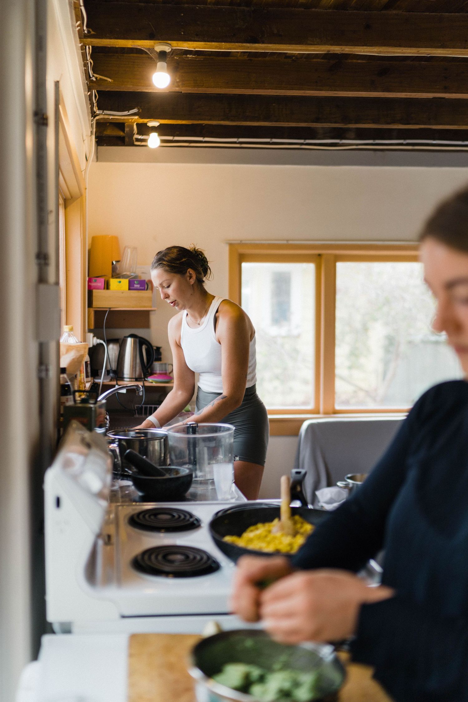 People preparing healthy food in rustic kitchen with exposed ceiling beams.