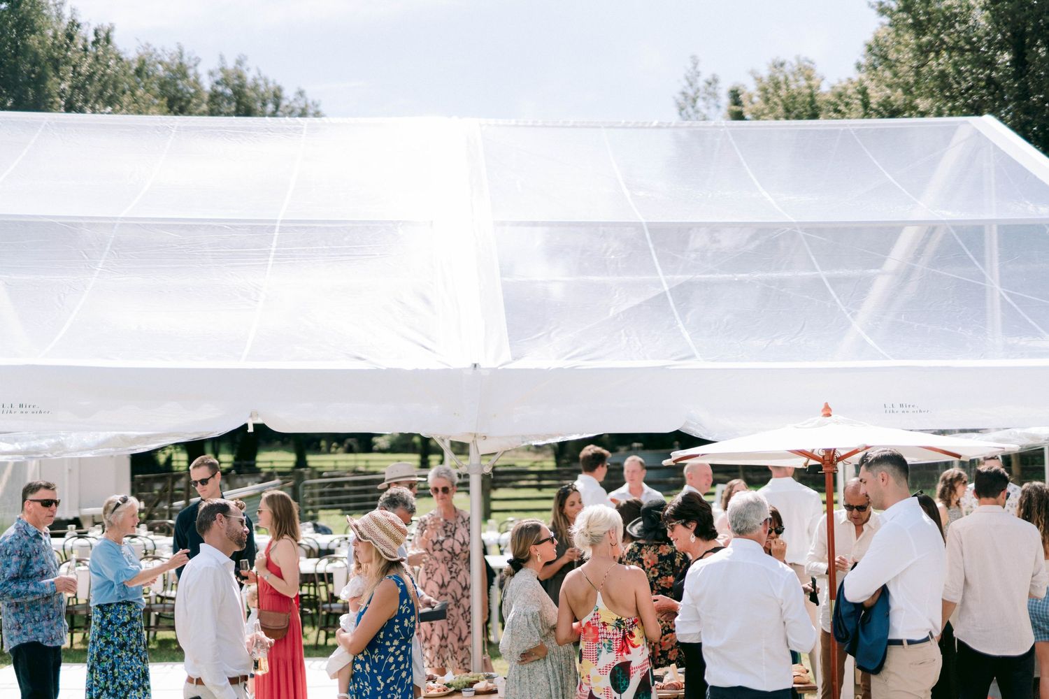 Large white wedding tent set up outdoors with guests enjoying the celebration.