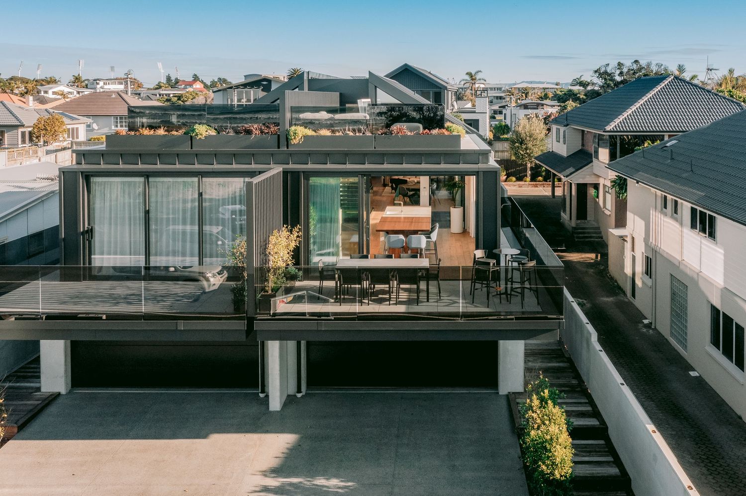 Rooftop terrace view of contemporary residential buildings with glass balustrades under blue sky.