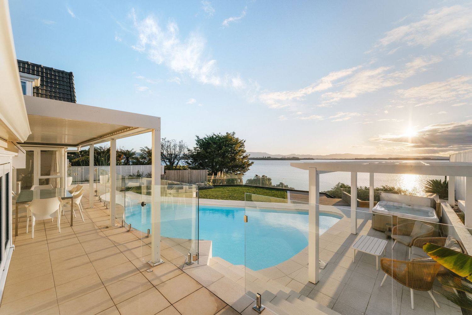 Luxurious infinity pool overlooking the ocean at sunset with modern white architecture.