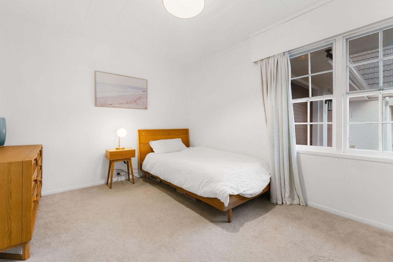 Bright empty bedroom with white walls and natural light streaming through windows.