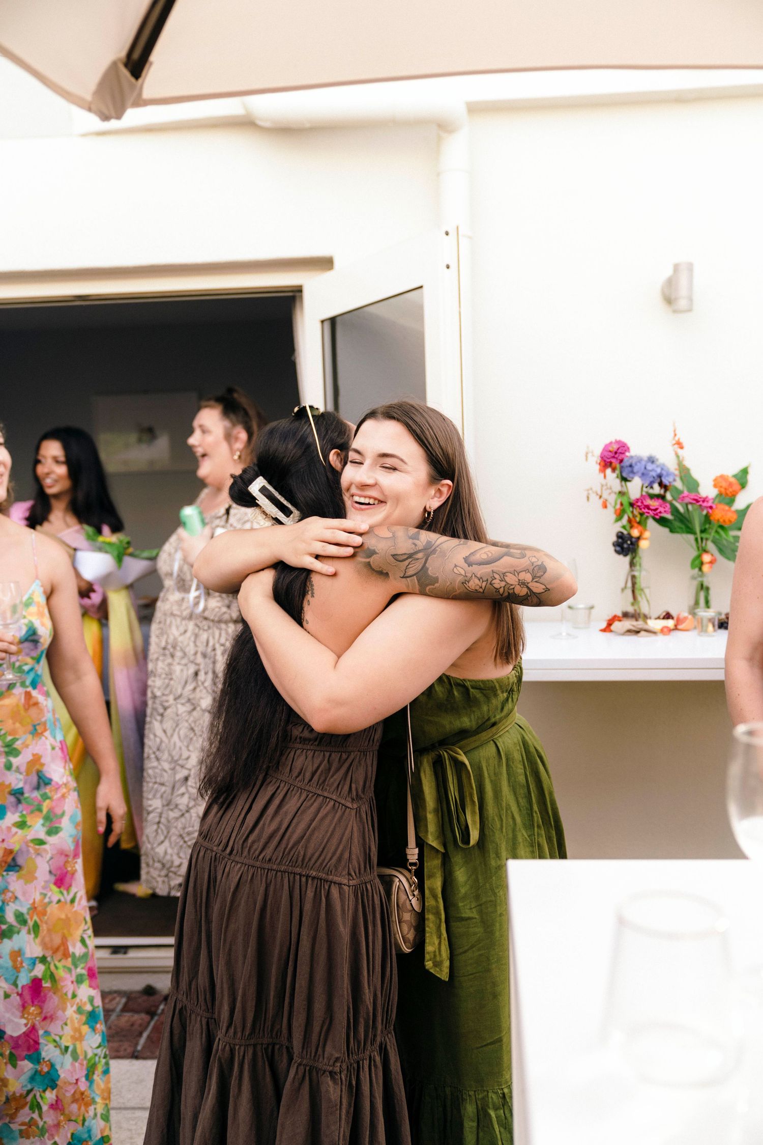 Joyful celebration with guests in colorful dresses dancing and embracing at indoor party.