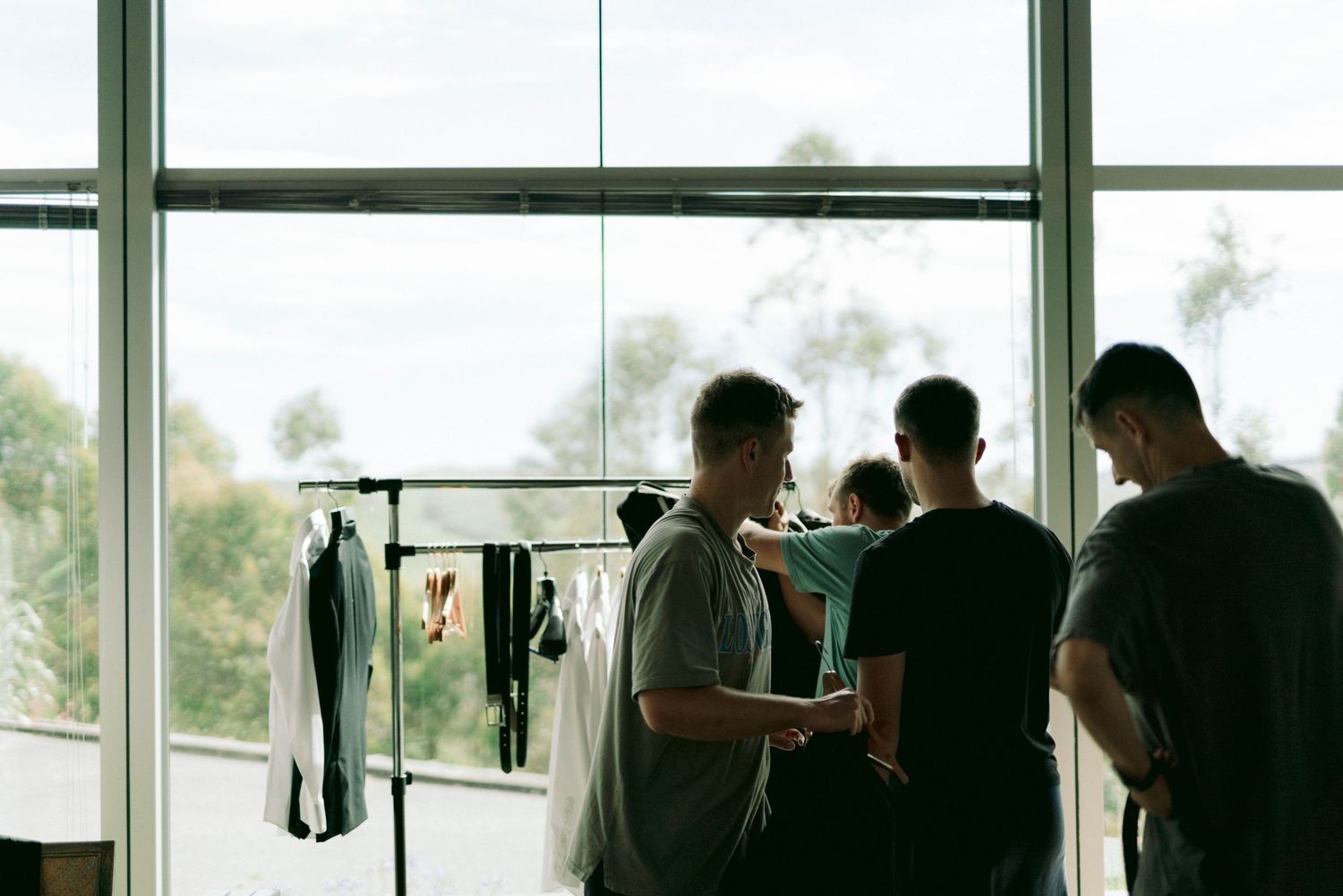 Silhouettes of wedding guests gathered by large windows with scenic mountain views.