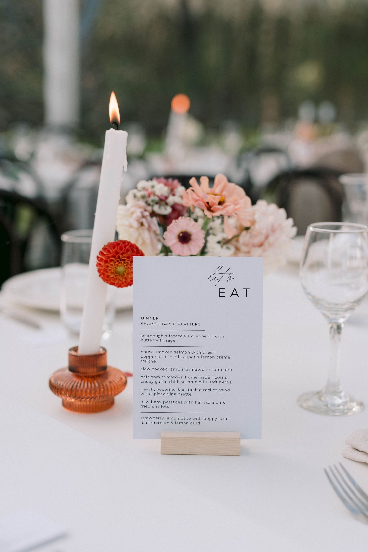 Elegant table setting with pink flowers and menu cards at an outdoor reception.