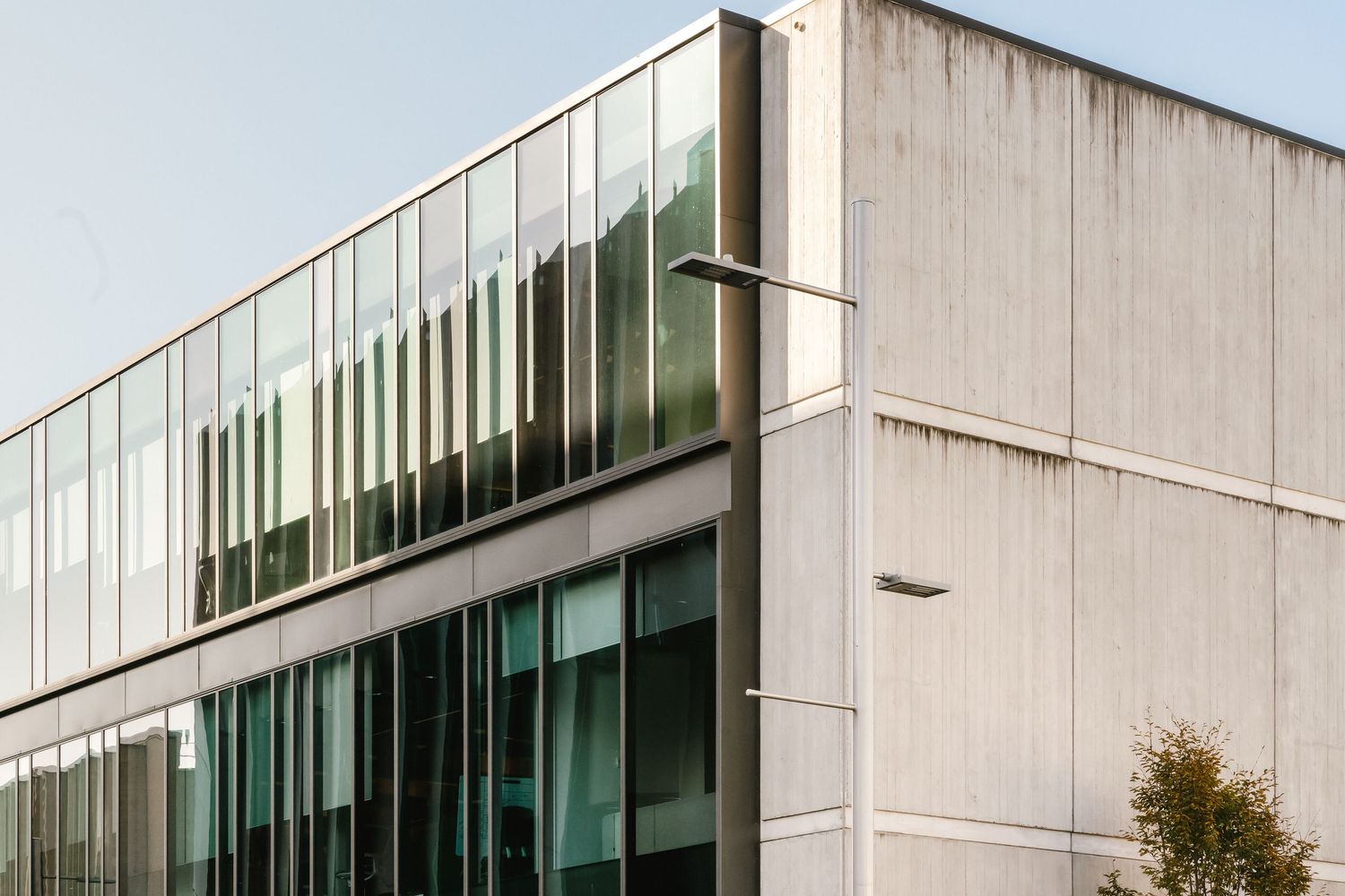 Modern office building exterior features angular glass and concrete architecture with large reflective windows.