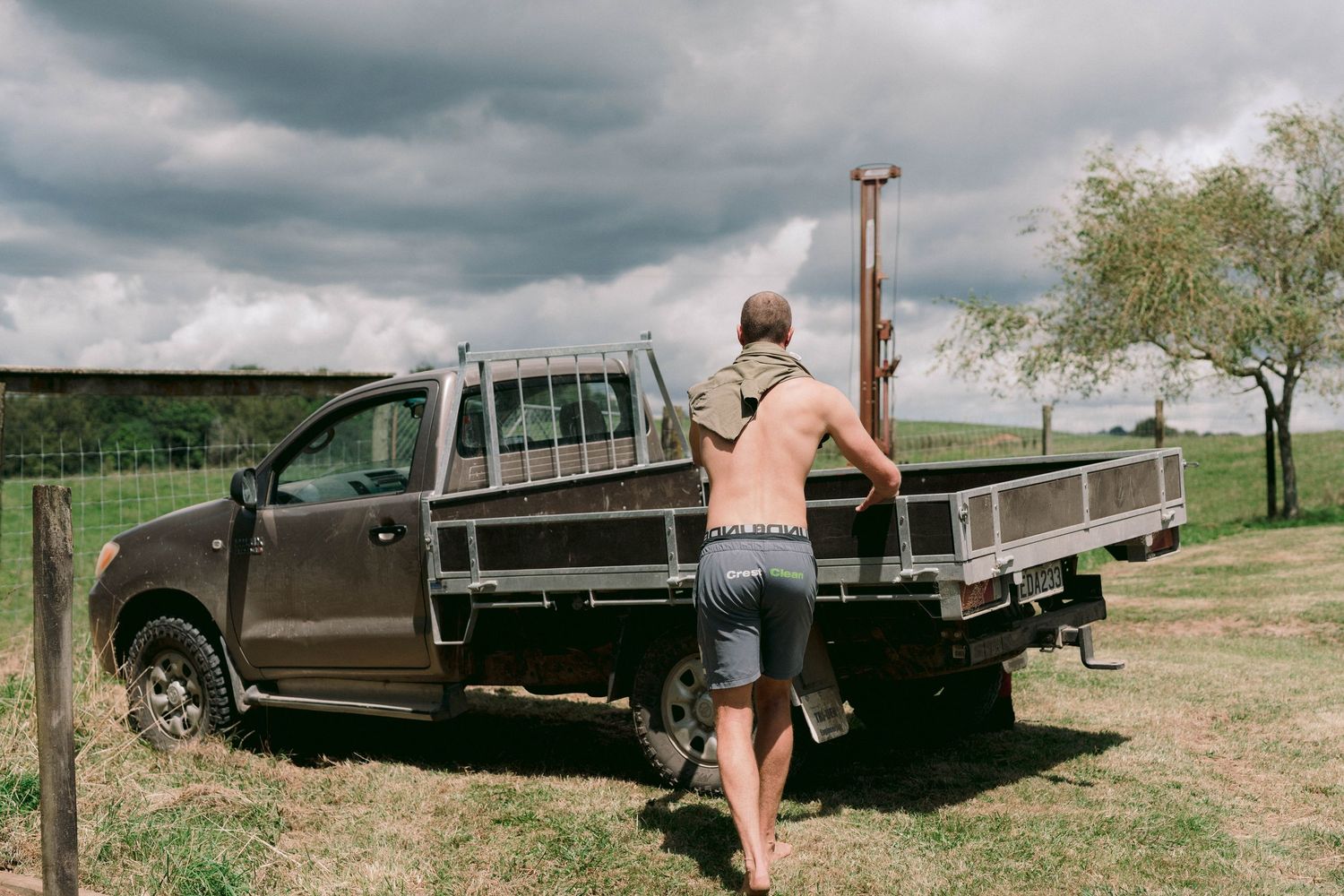 Vintage trucks and vehicles parked on grassy terrain under dramatic cloudy skies.