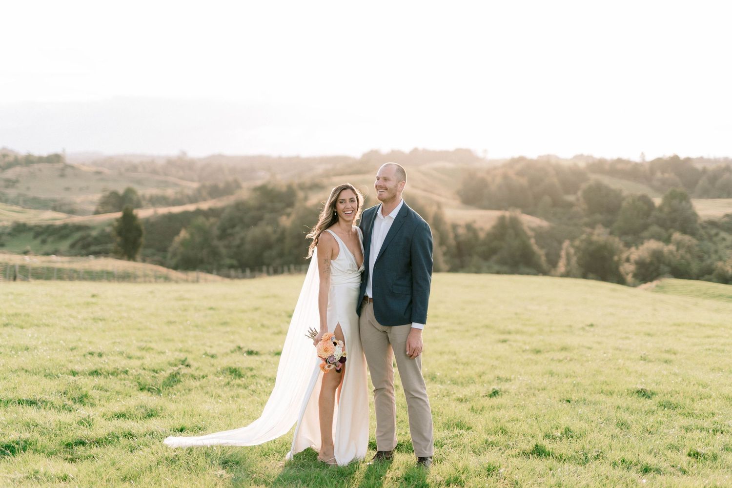 A romantic wedding photoshoot in a field during golden hour sunset.