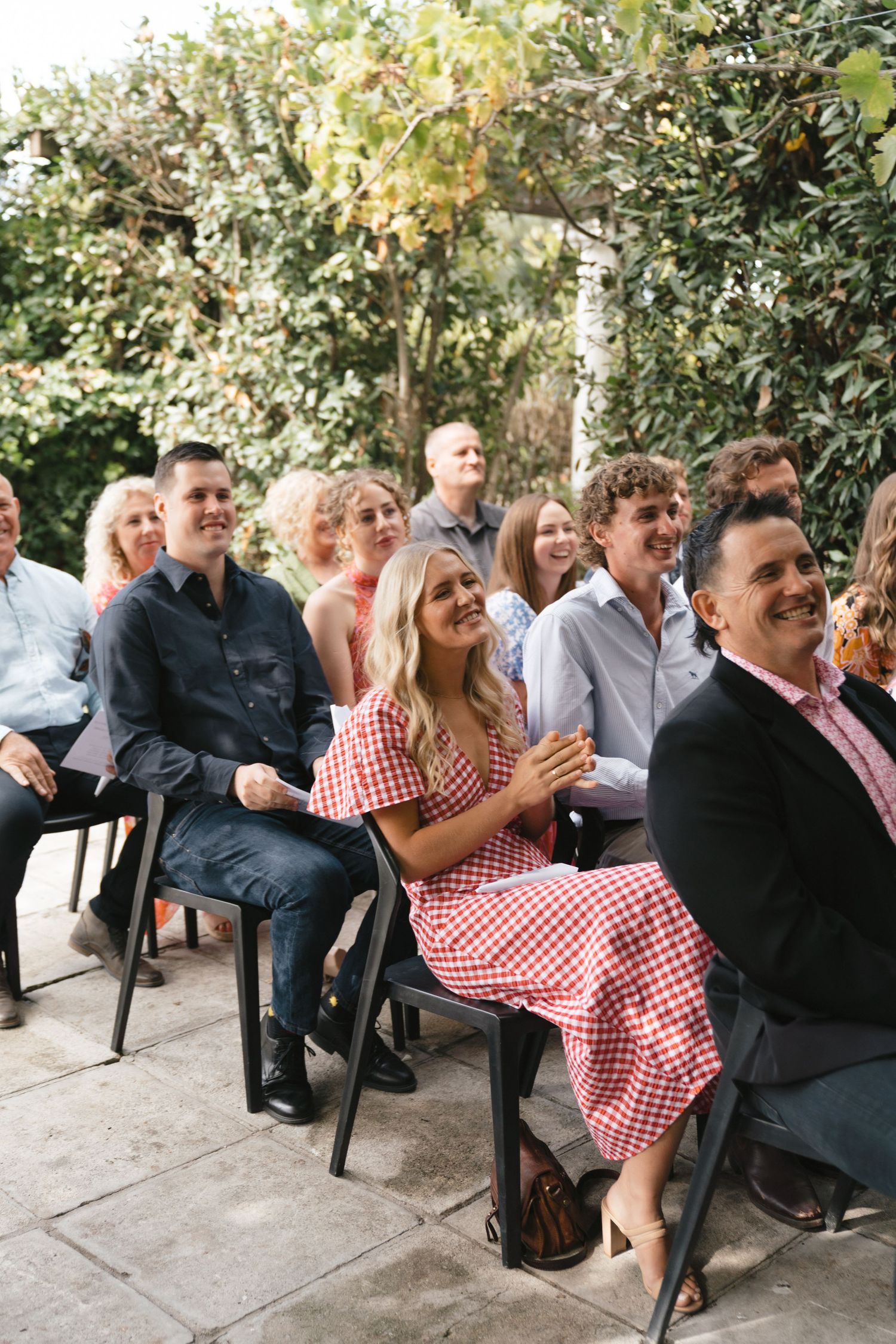 Wedding guests smiling and enjoying outdoor ceremony seating.