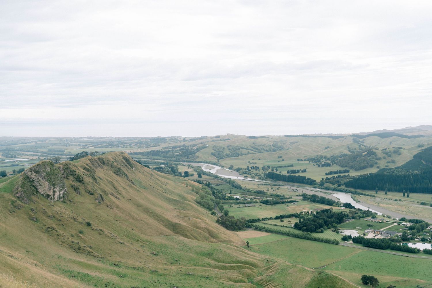 Panoramic view of rolling green hills and valleys under cloudy skies.