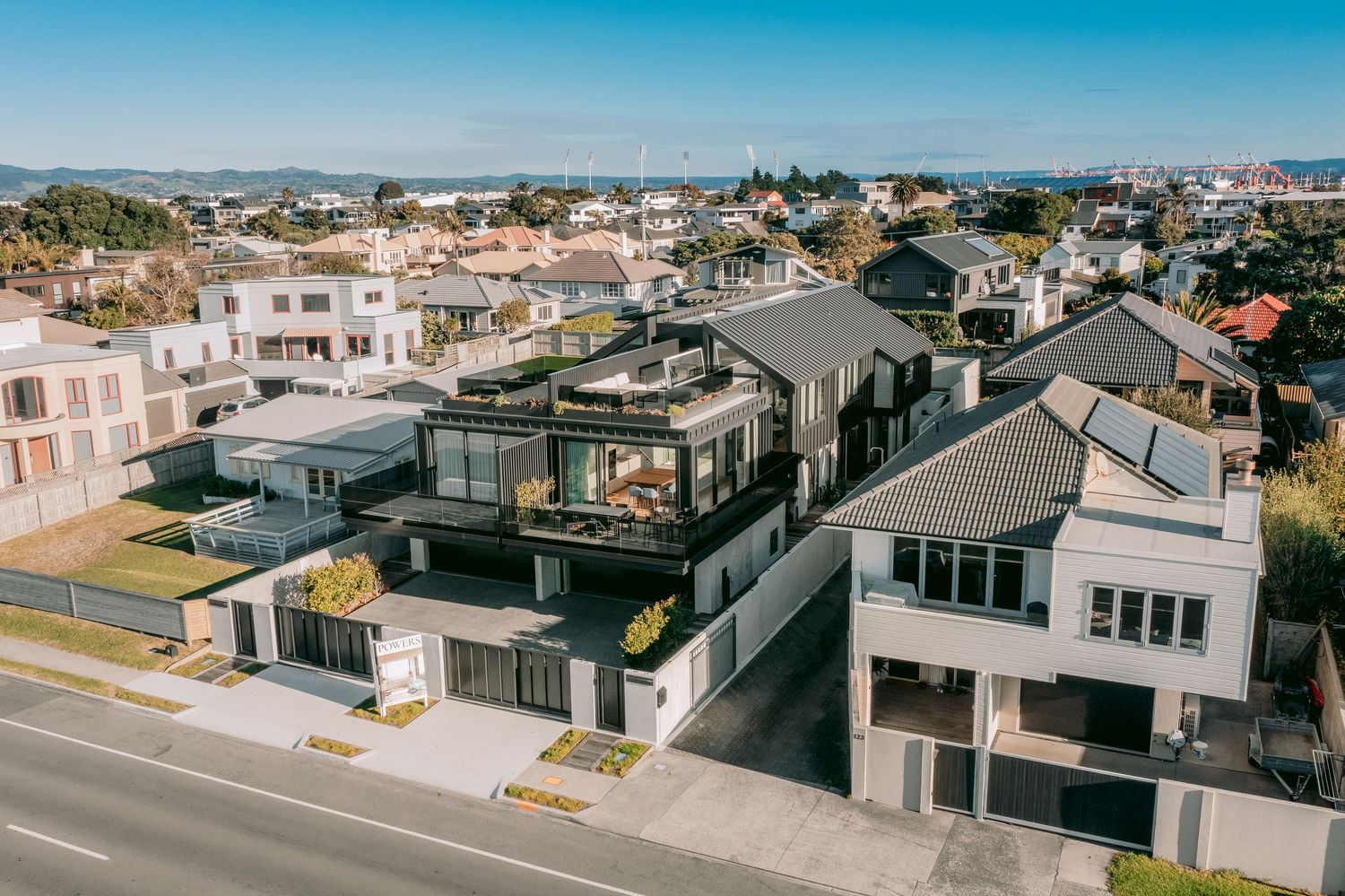 Aerial view of contemporary residential neighborhood with modern architecture and coastal scenery.