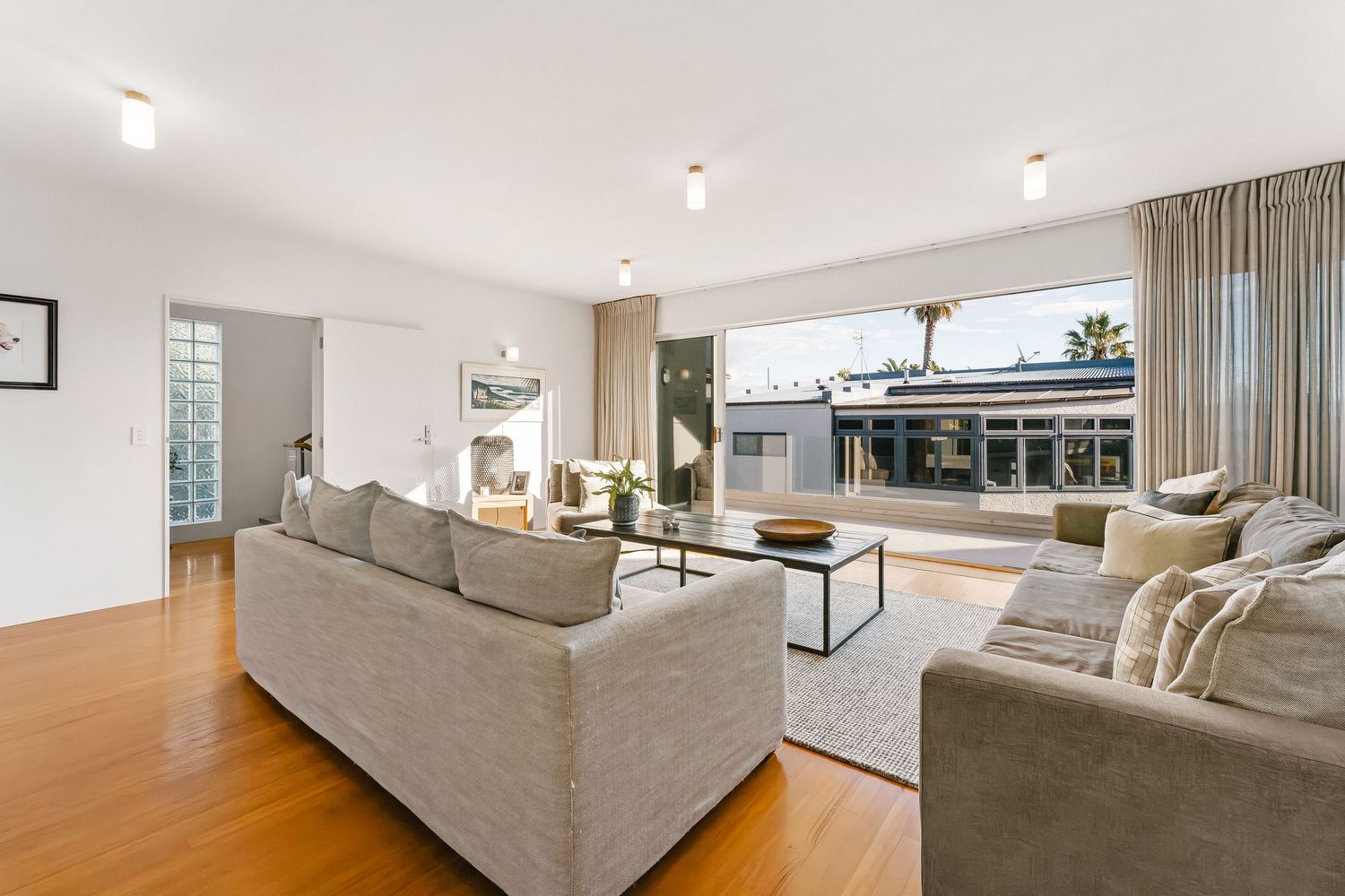 Contemporary living space showcases neutral tones with plush sectional and recessed lighting.