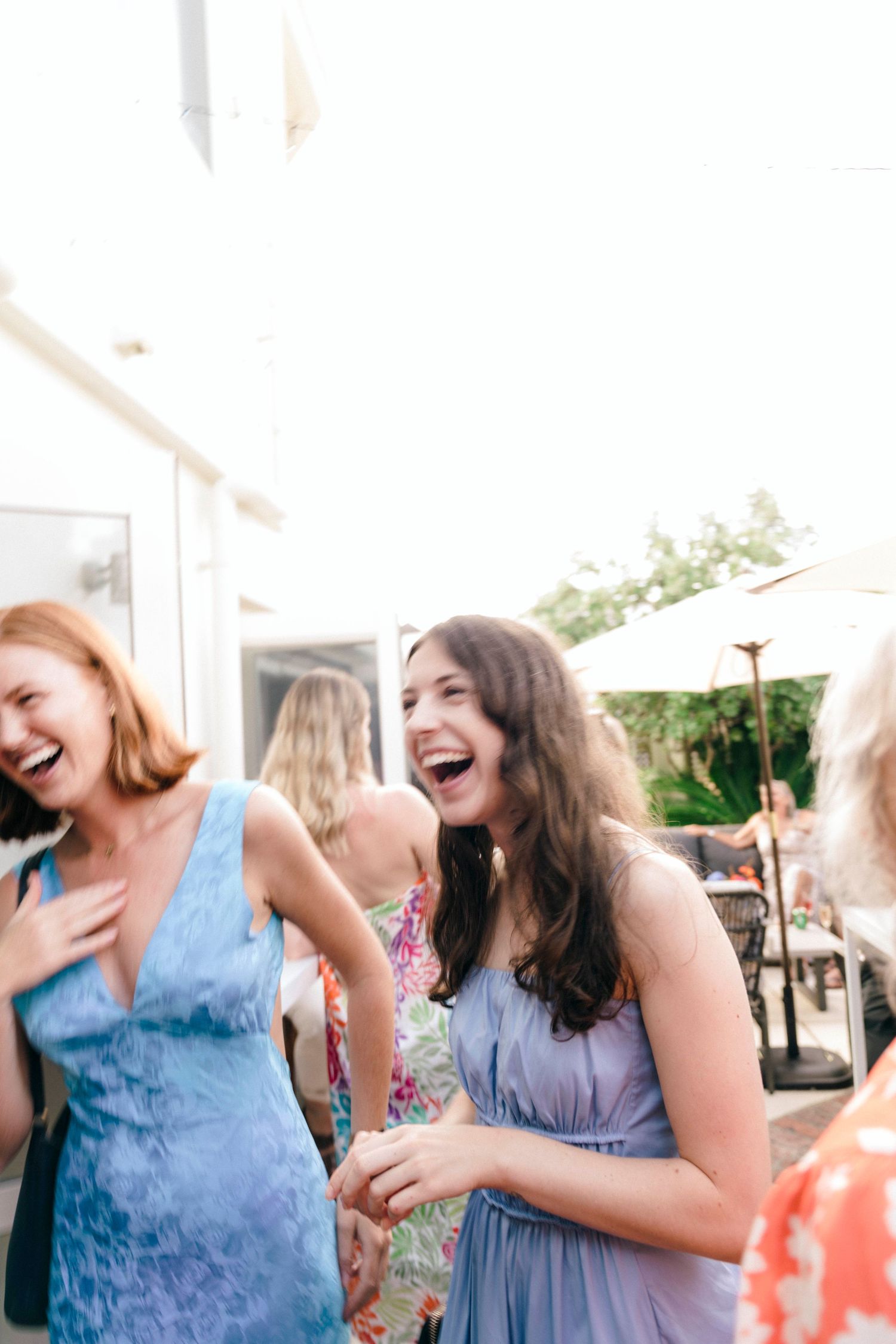 Friends share a moment of laughter during a festive outdoor gathering.
