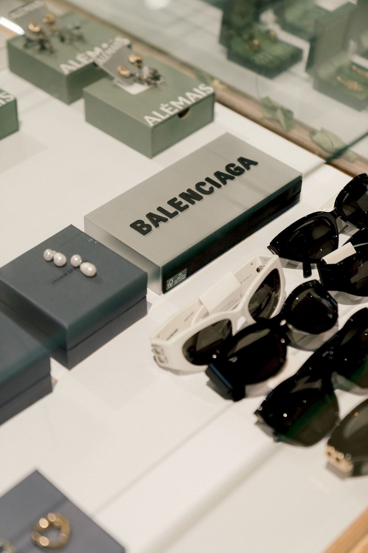 Balenciaga logo box displayed with collection of black sunglasses on white surface.