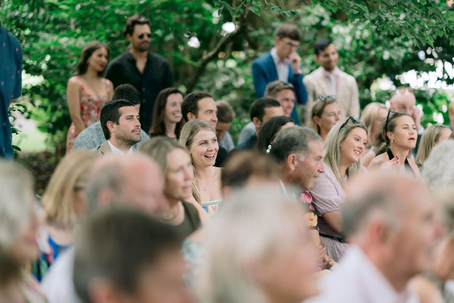 Wedding guests watching ceremony outdoors on a sunny afternoon.
