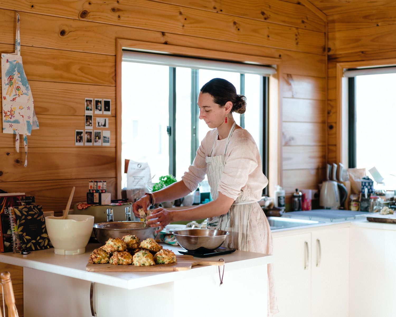 A panoramic view of a modern kitchen with pine walls and white countertops showing cooking preparation.