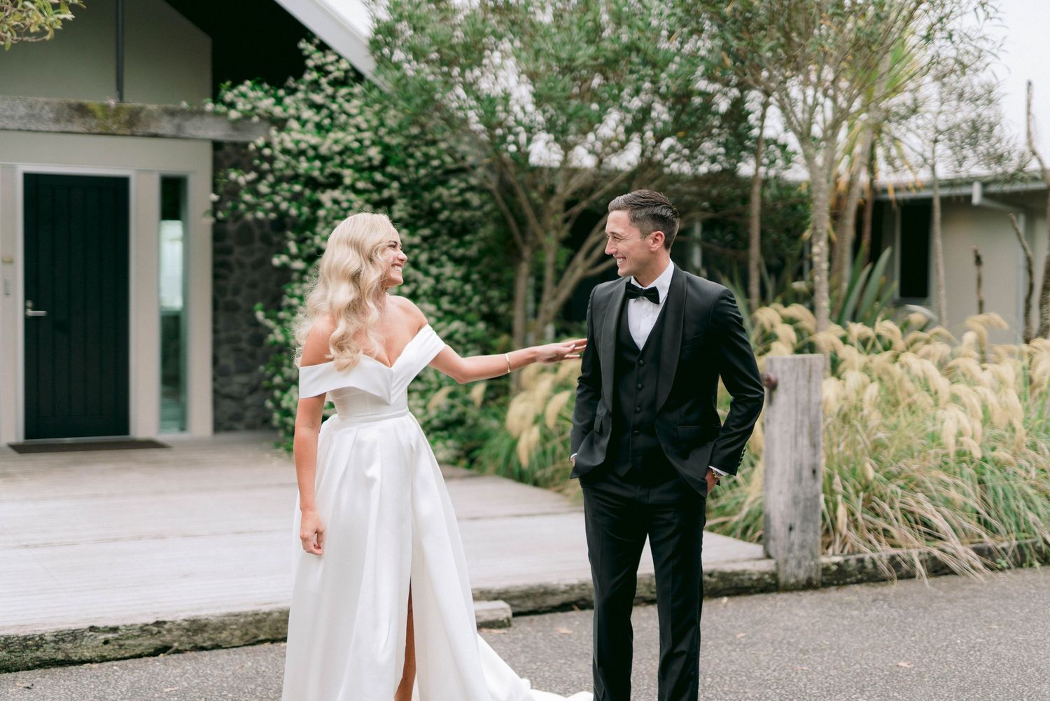Newlyweds sharing joyful moment outside chapel surrounded by greenery.