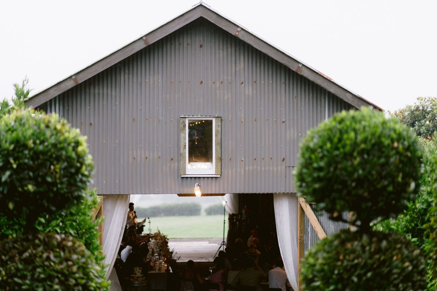 Exterior view of a modern gray barn-style wedding venue with manicured landscaping.