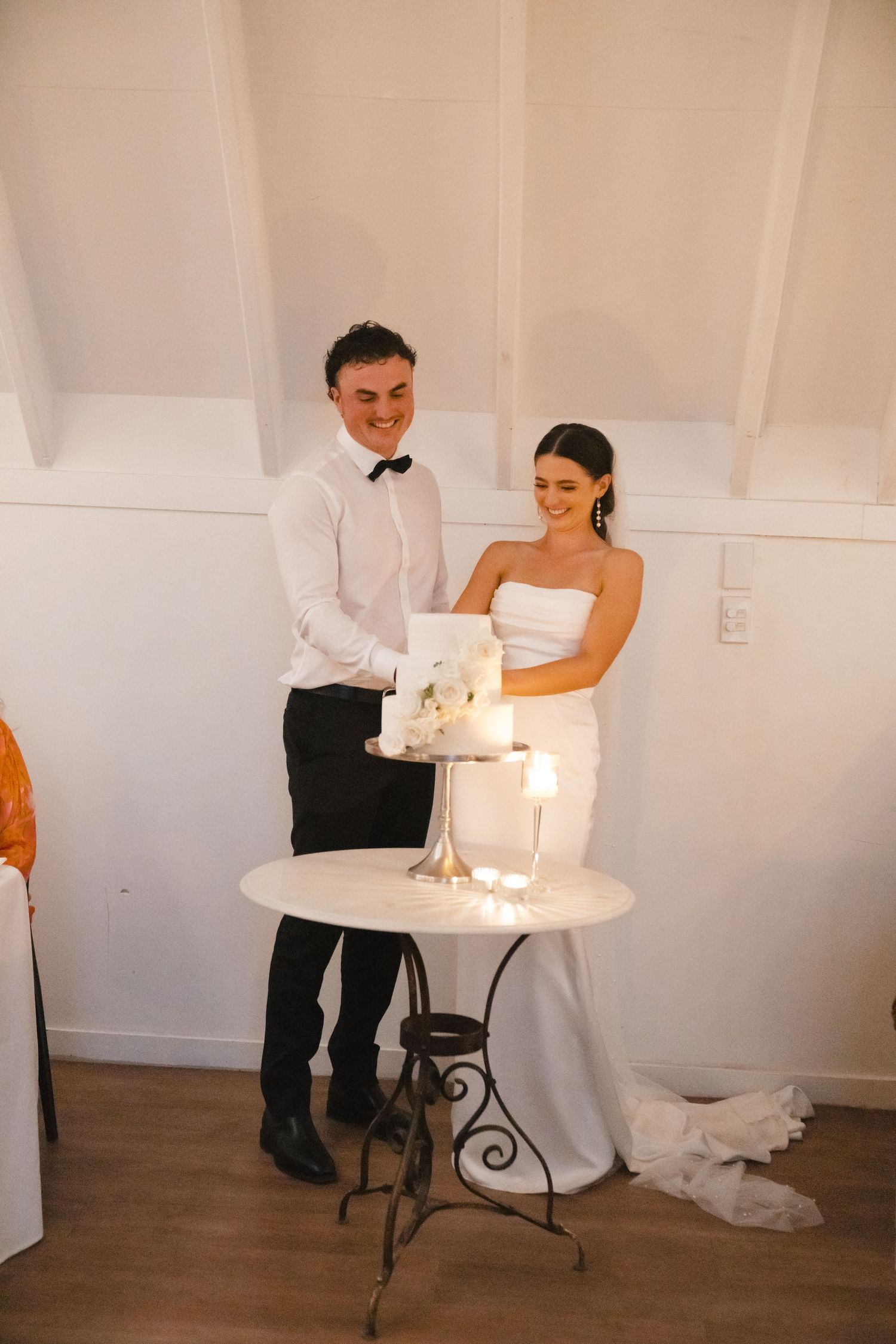 Wedding reception venue setup with intimate candlelit table and white decor against light colored walls.